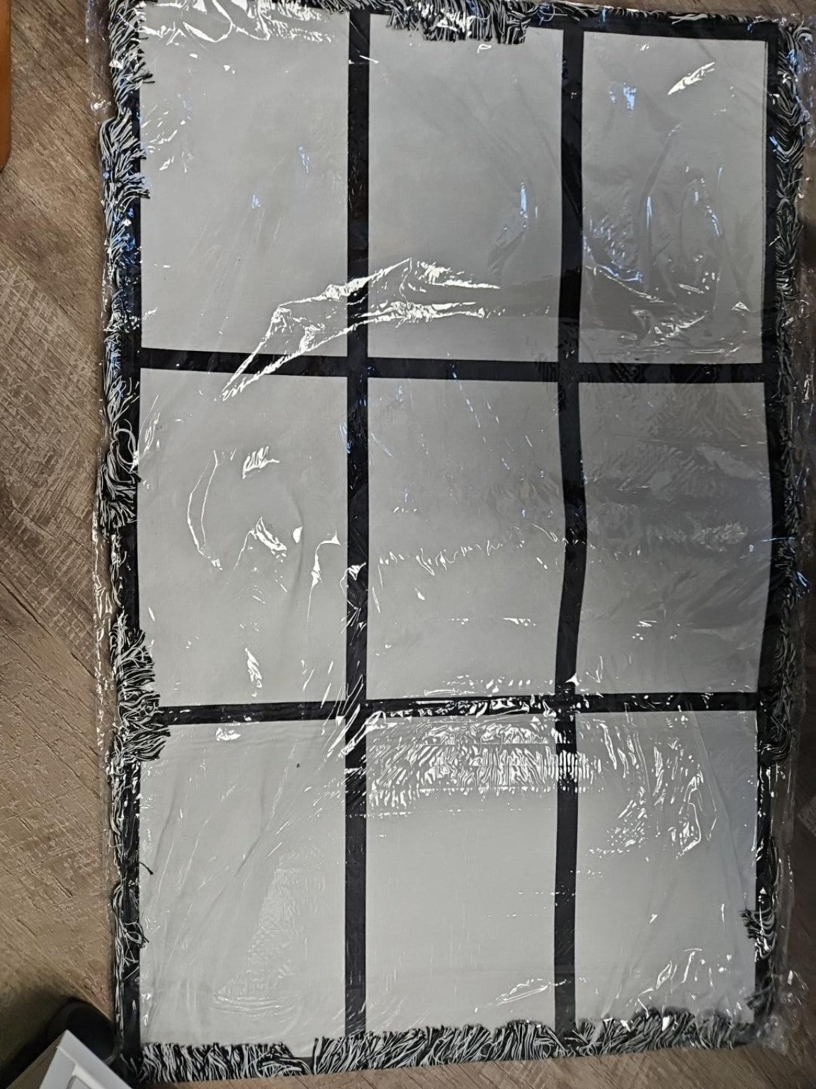 Black fringed nine-panel sublimation photo rug blank with nine white rectangular printing areas, shown in packaging