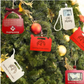 Wooden Christmas money holder ornaments on a tree including gas pump, gas can, purse, and photo frame designs