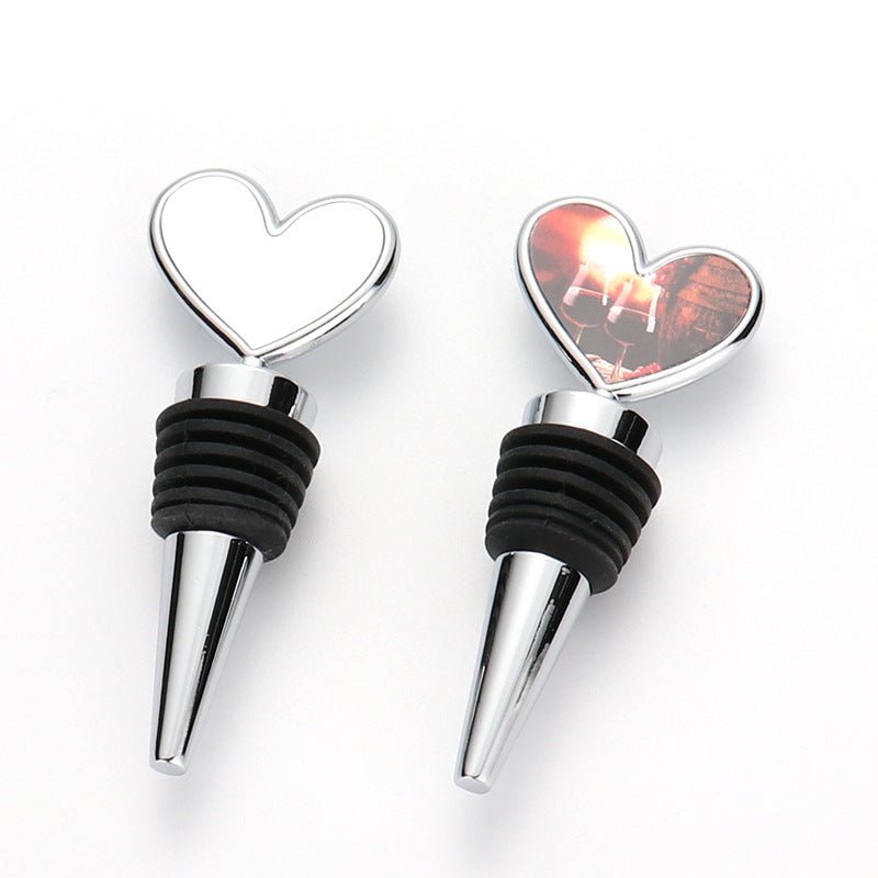 Two heart-shaped sublimation bottle stoppers, one blank chrome and one printed with a sunset wine photo